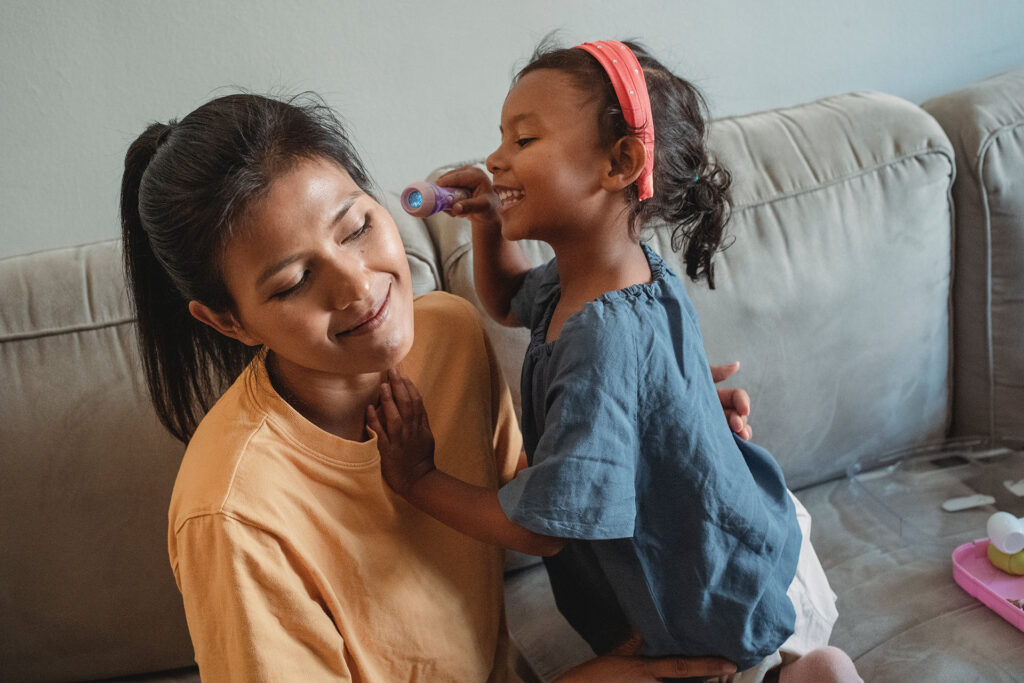 A young preschool girl playing doctor with her mother.